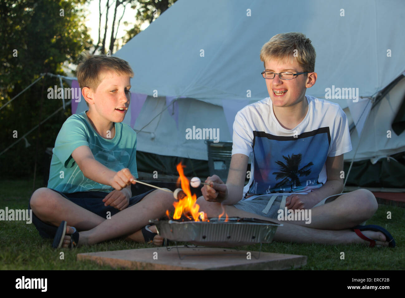Children toasting marshmallows over a camp fire whilst glamping camping in the UK Stock Photo