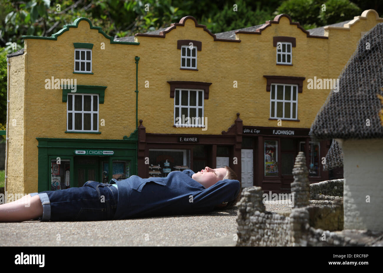 A boy relaxing in the sunshine during a visit to The Model Village in Godshill on the Isle of Wight Stock Photo