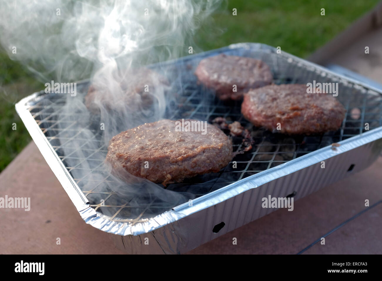 Burgers cooking on a disposable barbecue BBQ Stock Photo Alamy