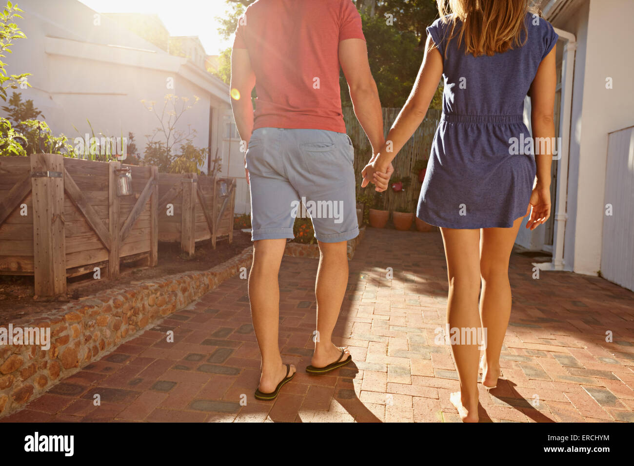 Cropped shot of young couple walking towards their house together. Rear view of couple in backyard taking walk on a bright sunny Stock Photo