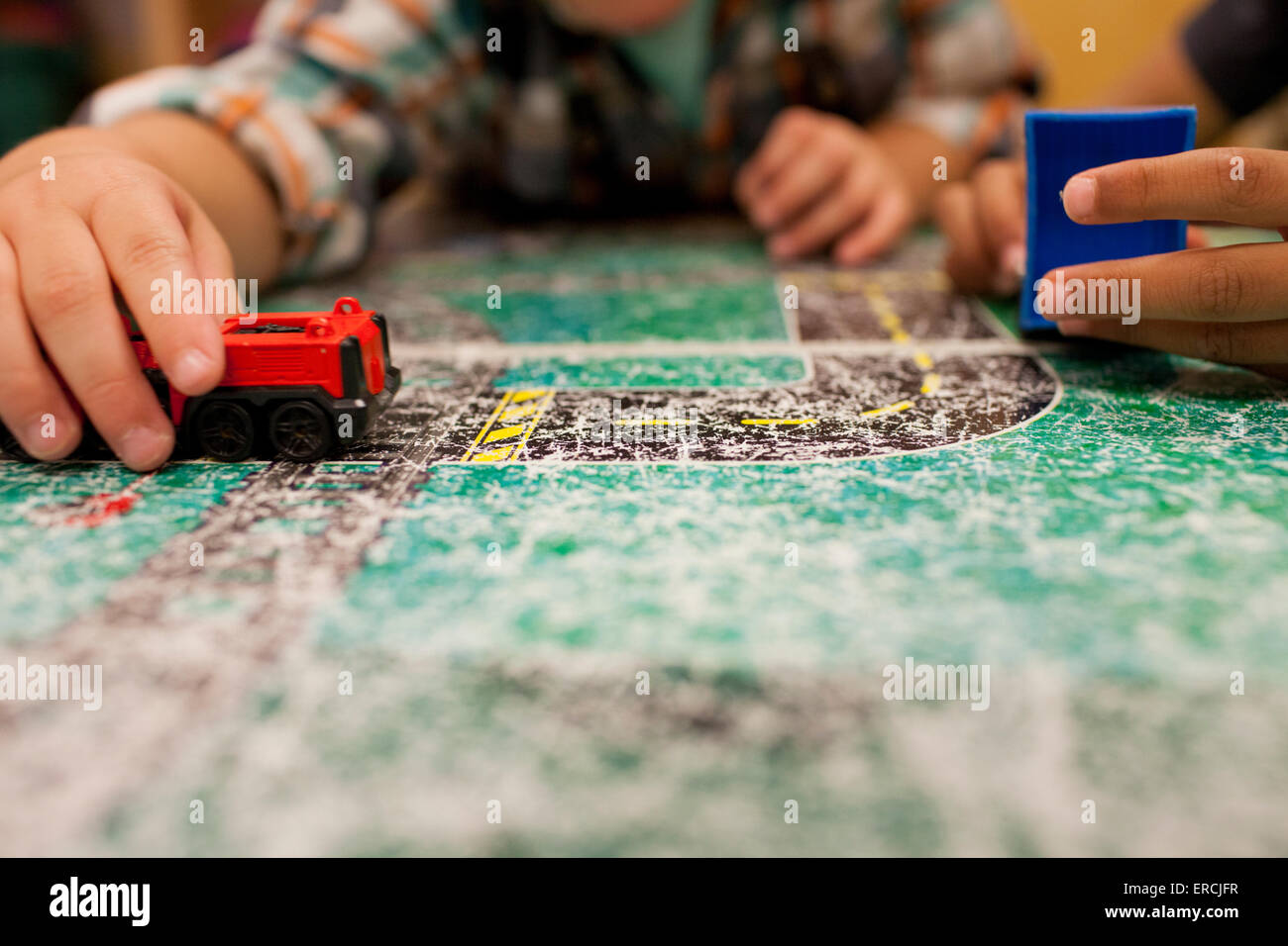 Two young boys play with toy cars on a roadmap table. Stock Photo