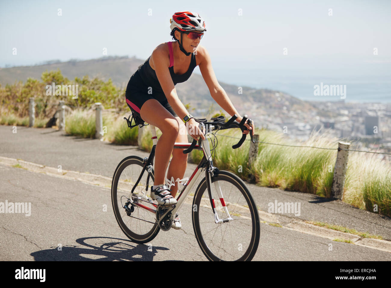 Woman practicing for triathlon competition. Triathlon athlete cyclist downhill on country road. Young woman riding bicycle on o Stock Photo