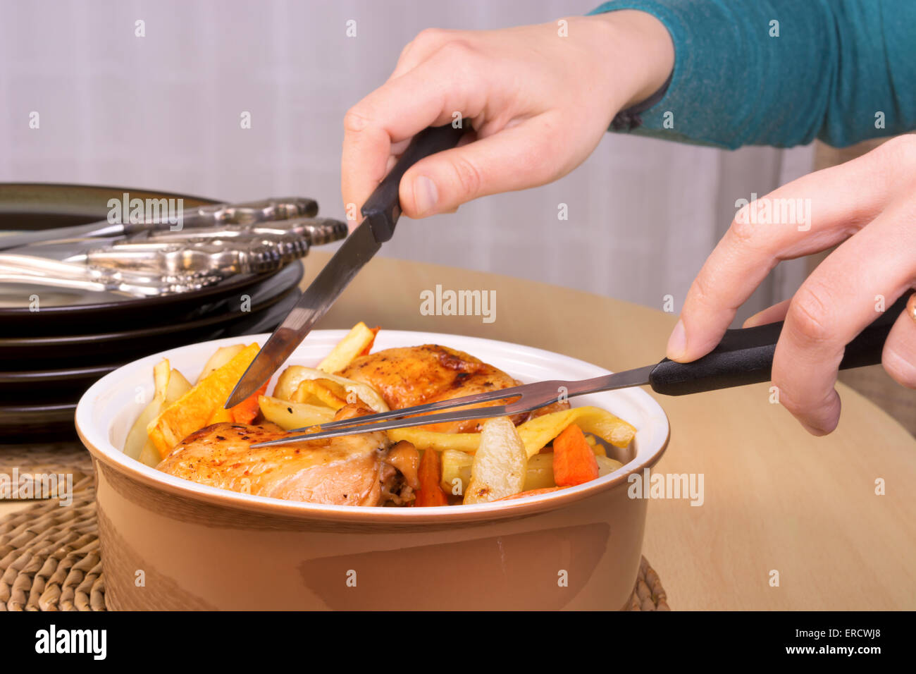 Close up of the hands ready to serve roasted chicken legs and vegetables Stock Photo