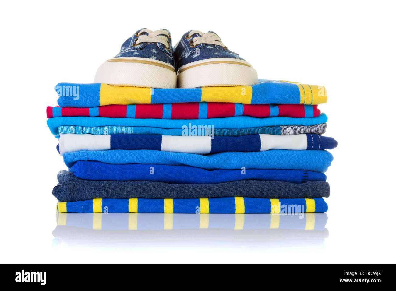 Stack of colourful summer shirts and a pair of sneakers on top isolated on white background Stock Photo