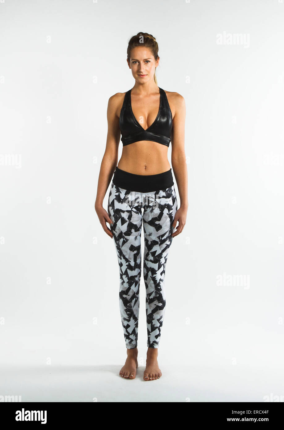 Young woman stood against white backdrop modeling sportswear clothes with  different yoga positions Stock Photo - Alamy