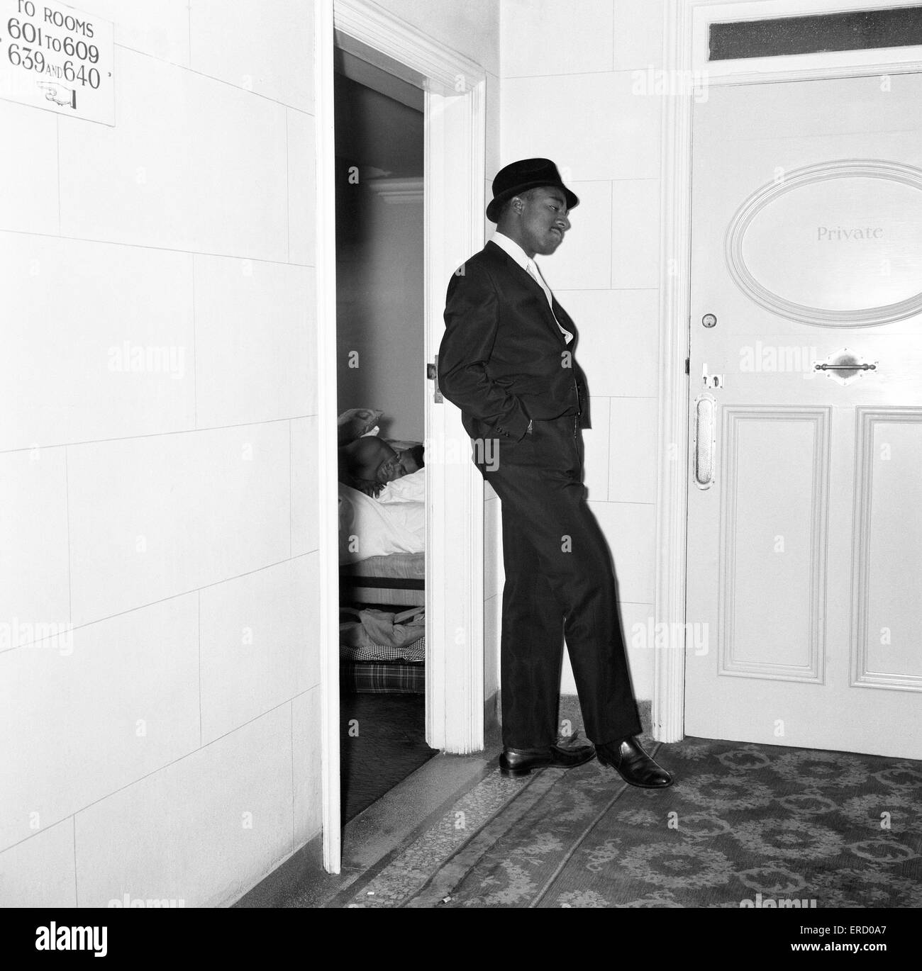 Cassius Clay's bodyguard Ronald King keeps watch outside the Piccadilly Hotel room where Clay is asleep. 26th May 1963 Stock Photo