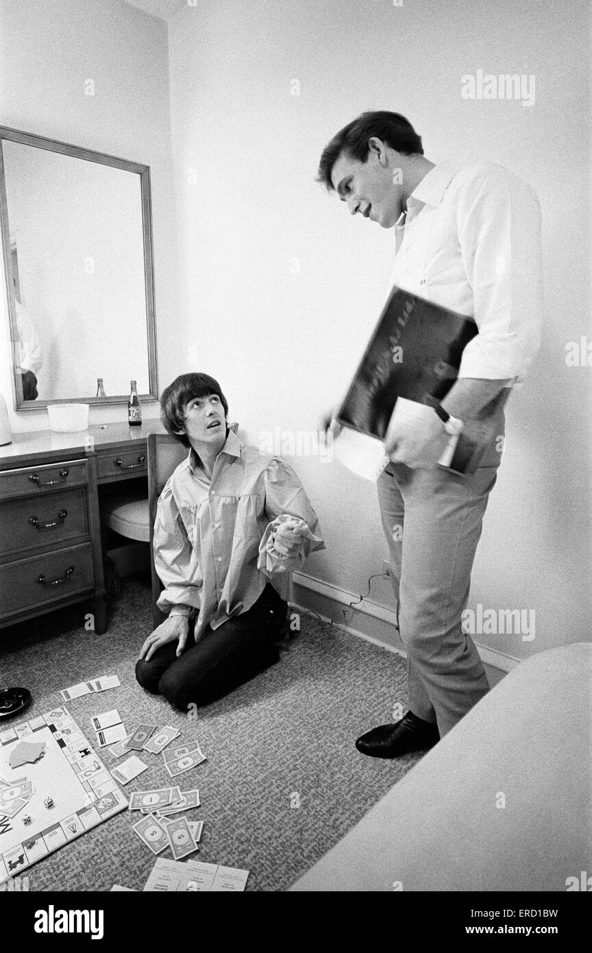 George Harrison speaks with Neil Aspinall while enjoying a game of Monopoly with singer songwriter Jackie de Shannon (not pictured), one of the tour's support acts, at the Lafayette Motor Inn, Atlantic City, New Jersey, USA, Sunday 30th August 1964. Summe Stock Photo