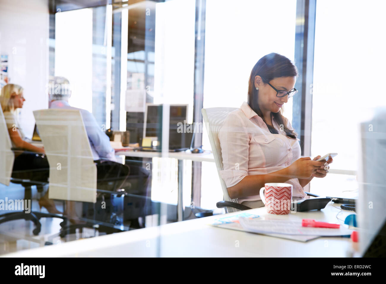 Woman using smart phone,phone at her desk in an office Stock Photo