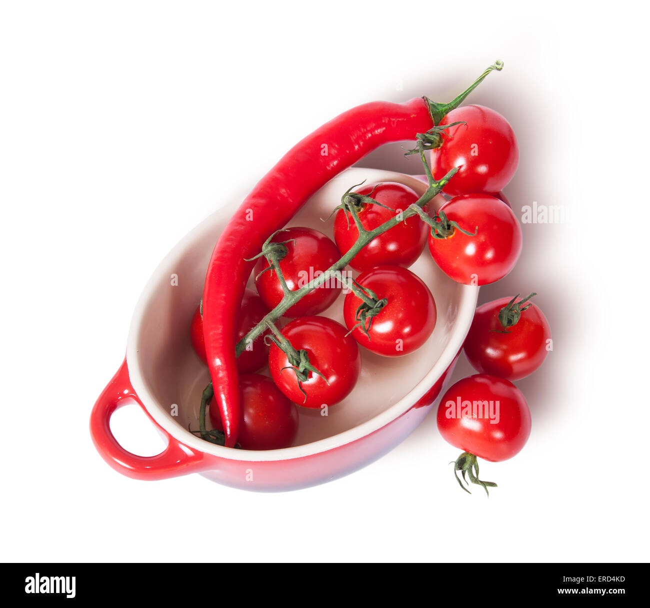 Cherry tomatoes and chili peppers in the saucepan top view isolated on white background Stock Photo