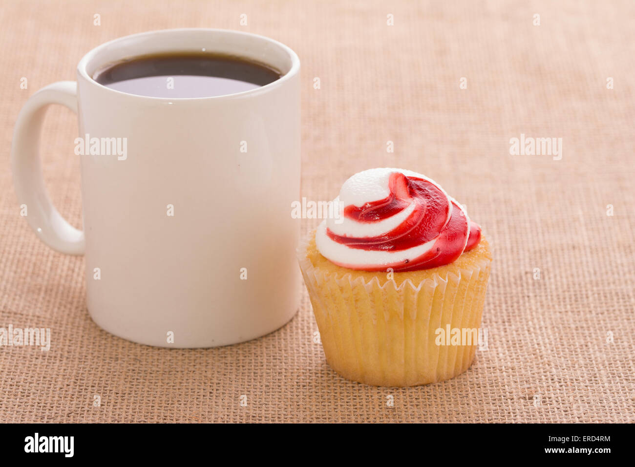 Coffee cup with a strawberry flavored cupcake, on burlap background Stock Photo