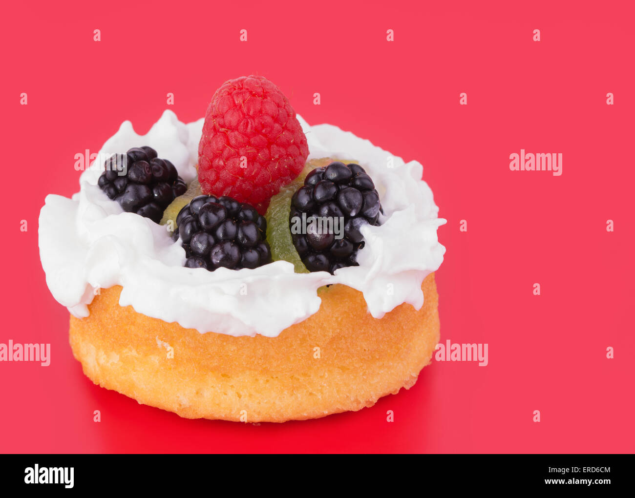 Blackberries, Kiwi, Raspberry and whipped cream topping a dessert shell, on red background Stock Photo