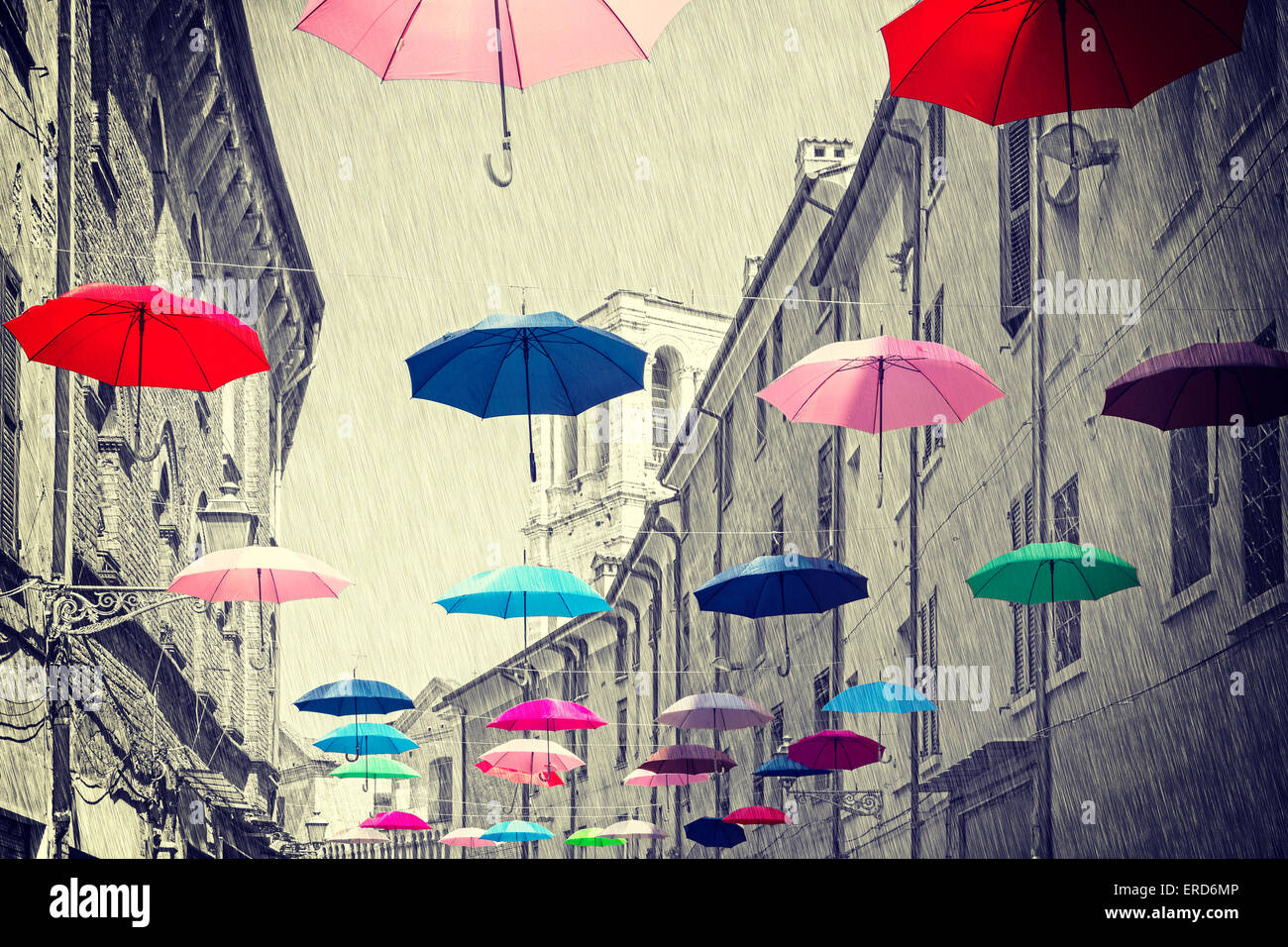 Retro vintage filtered colorful umbrellas hanging above street of Ferrara, black and white background. Stock Photo