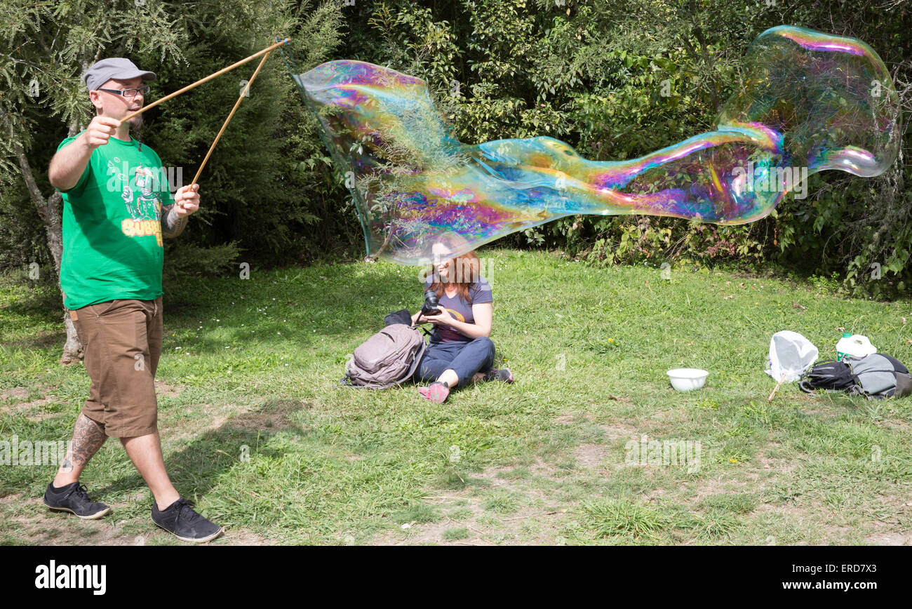 Giant soap bubble being formed by an expert bubble artist while his partner looks on Stock Photo