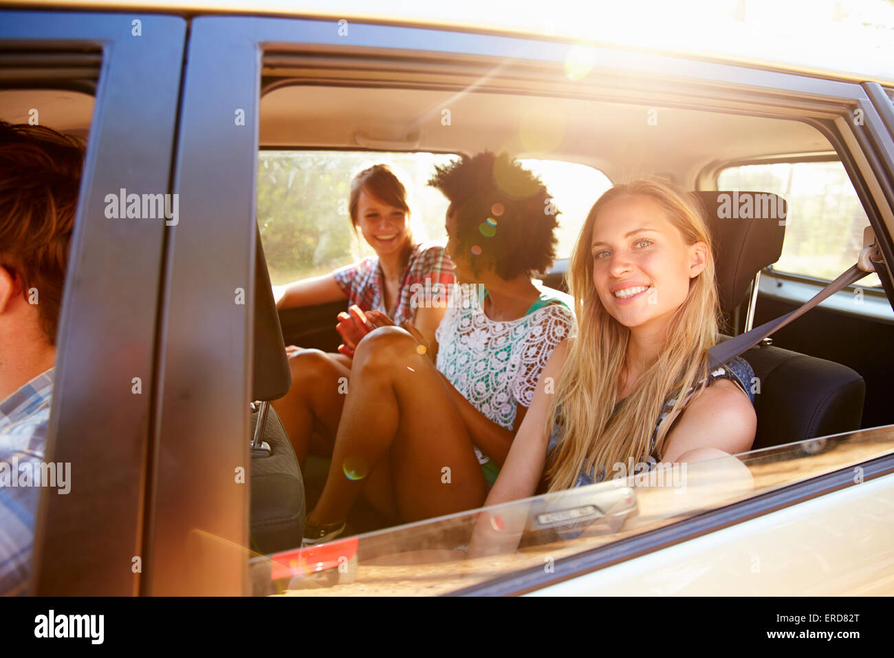 Three Women Sitting In Rear Seat Of Car On Road Trip Stock Photo