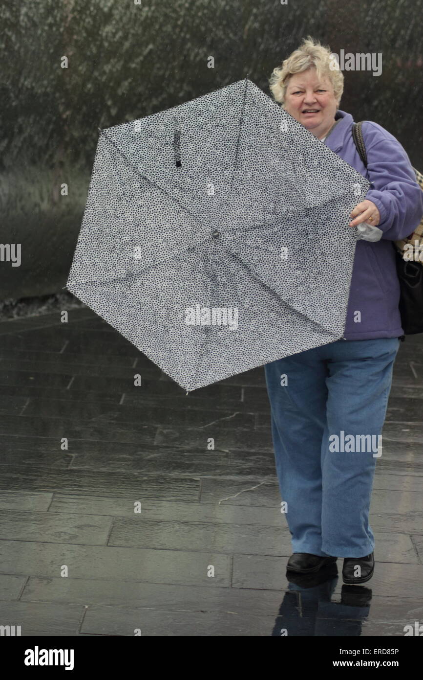 A woman struggles with her umbrella during rain and strong wind in Sheffield South Yorkshire England UK Stock Photo