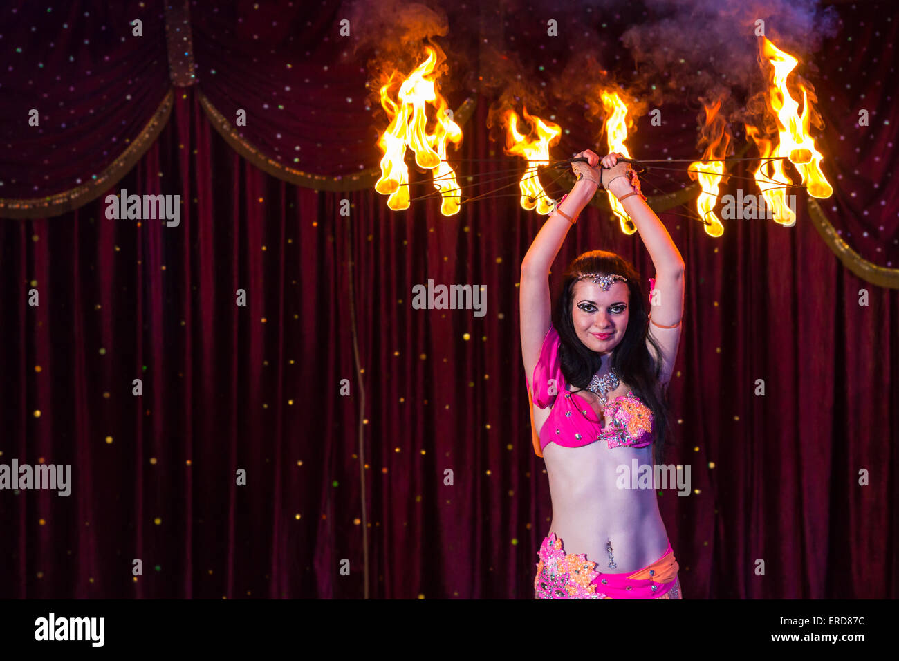 Exotic Female Fire Dancer Wearing Bright Pink Costume Twirling Flaming