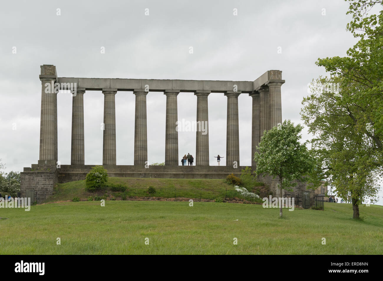 Tourists posing for photos at the unfinished National Monument of Scotland on Calton Hill on a windy grey day in Edinburgh Stock Photo