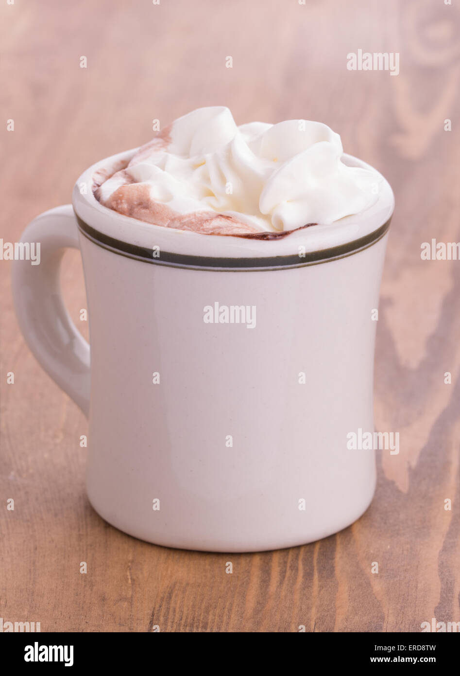 Hot chocolate with cream topping in an antique cup on rustic wooden table Stock Photo