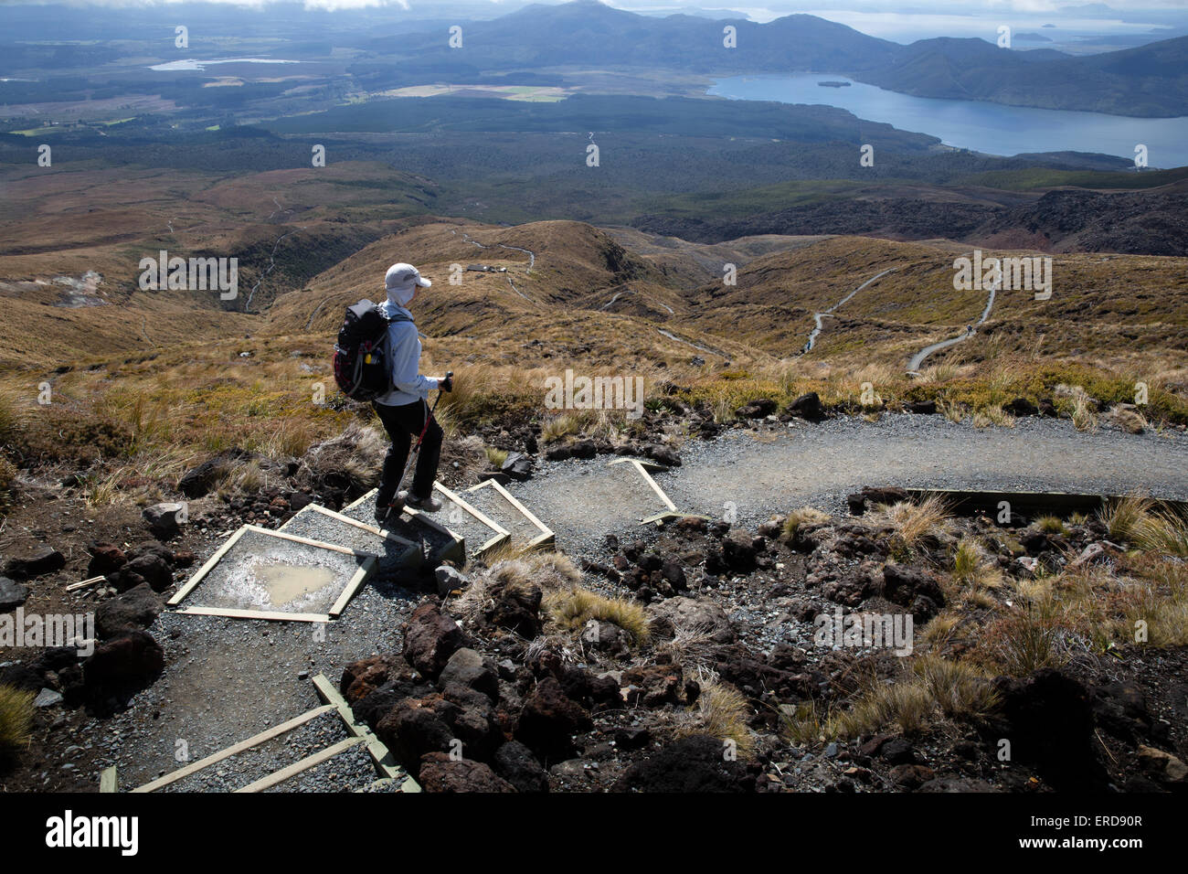 A female hiker in a white sun hat on the steep winding descent of th Tongariro Alpine Crossing in New Zealand Stock Photo