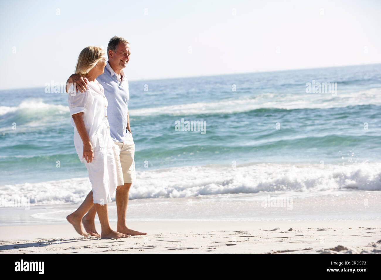 Senior Couple On Holiday Walking Along Sandy Beach Stock Photo - Alamy