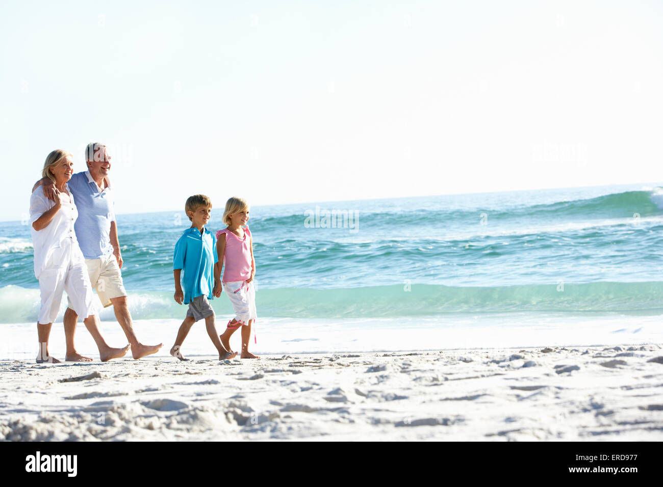 Grandparents and Grandchildren Walking Along Beach Stock Photo