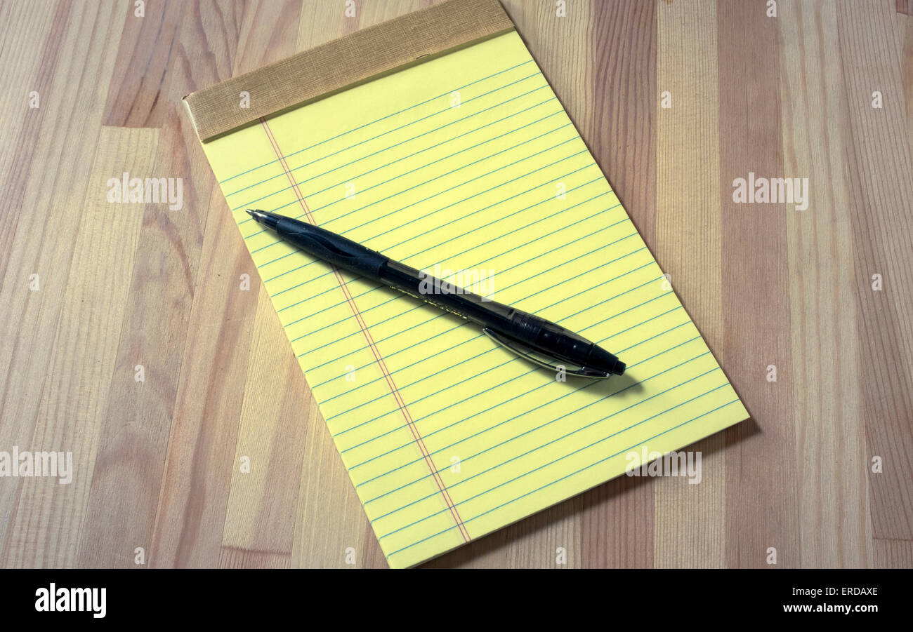 Small yellow legal pad and ball-point pen on wooden table Stock Photo