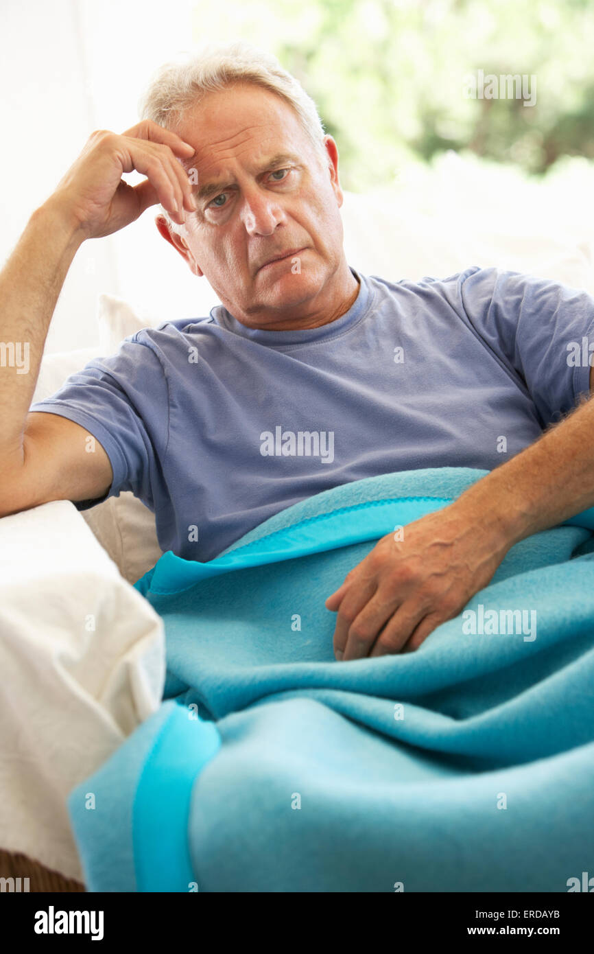 Senior Man Feeling Unwell Resting Under Blanket Stock Photo