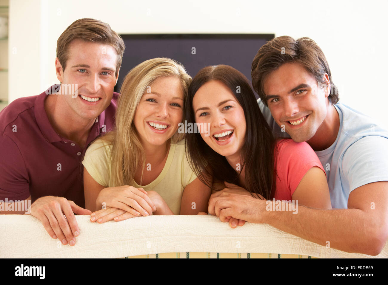 Group Of Friends Watching Widescreen TV At Home Stock Photo