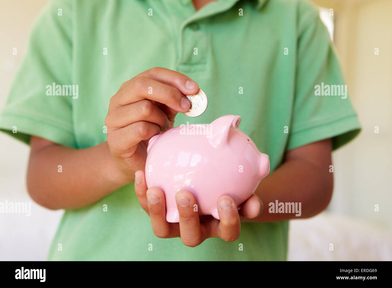 Young boy putting money in piggybank Stock Photo - Alamy