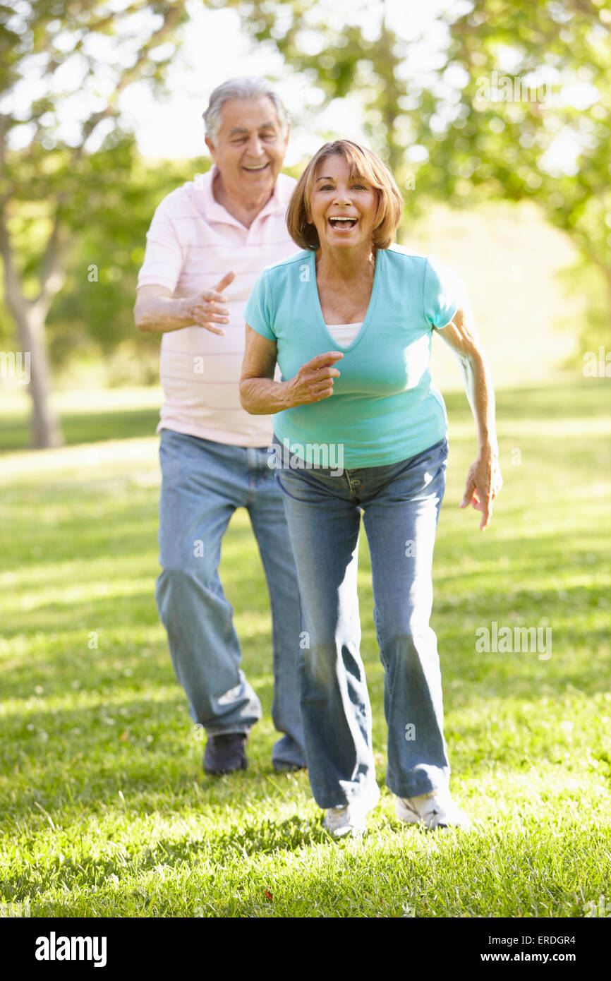 Senior Hispanic Couple Running In Park Stock Photo