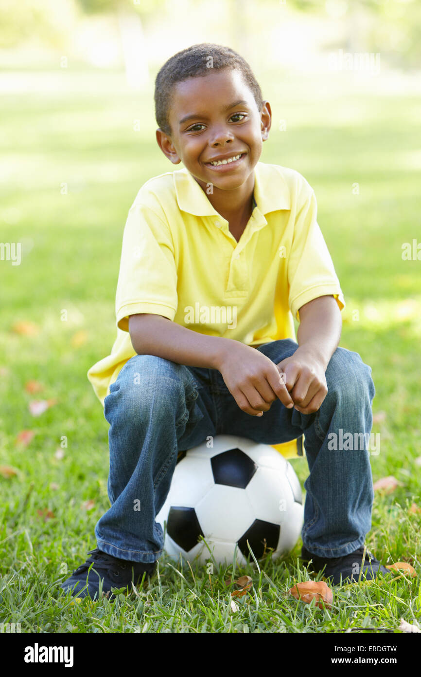 African American Boy Sitting On Football In Park Stock Photo - Alamy