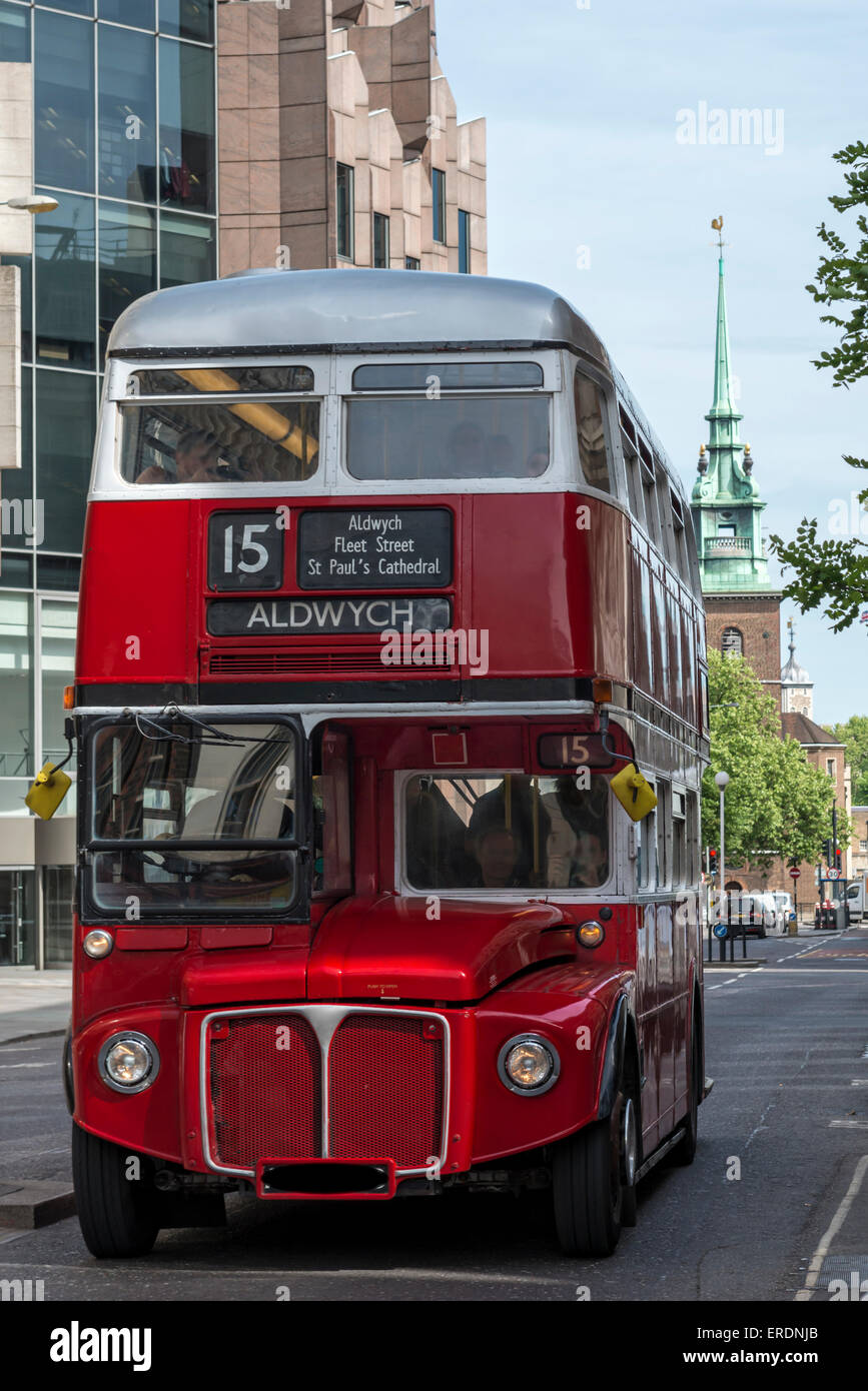 A vintage red and silver Routemaster London double decker bus driving along a city street Stock Photo