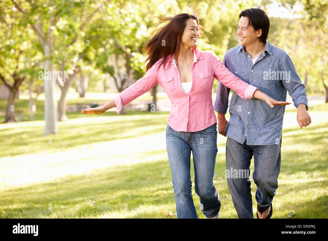 Asian couple running through in park Stock Photo - Alamy