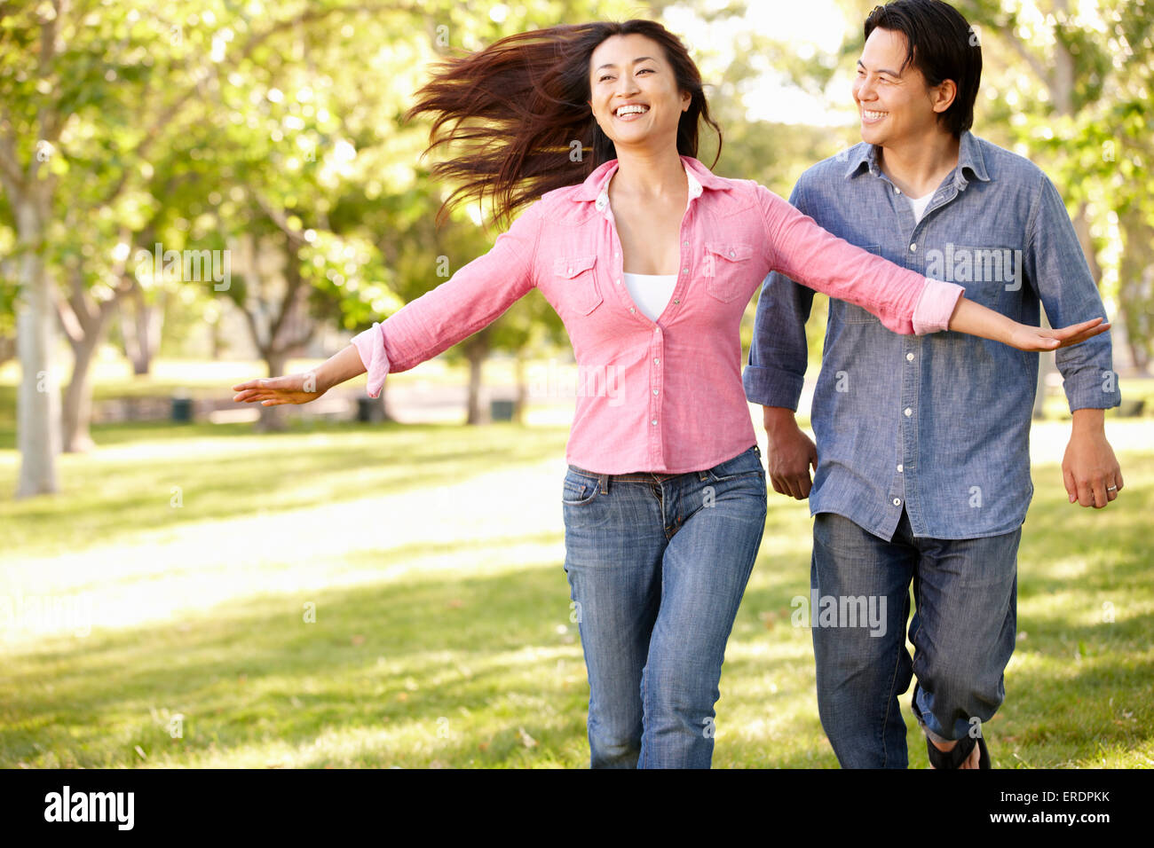 Asian couple running through in park Stock Photo - Alamy