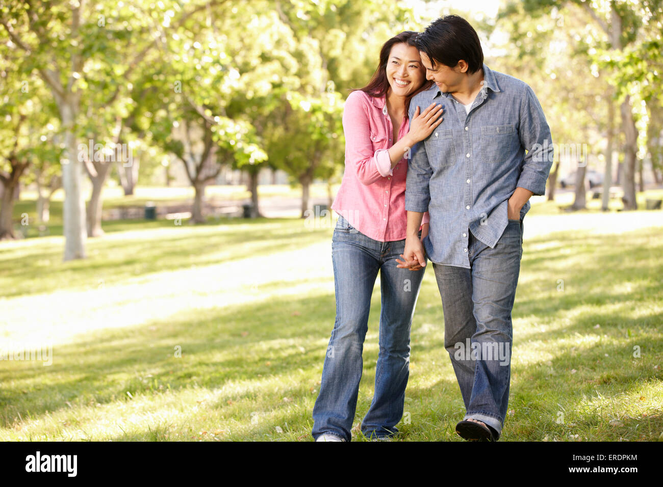 Asian couple walking hand in hand in park Stock Photo