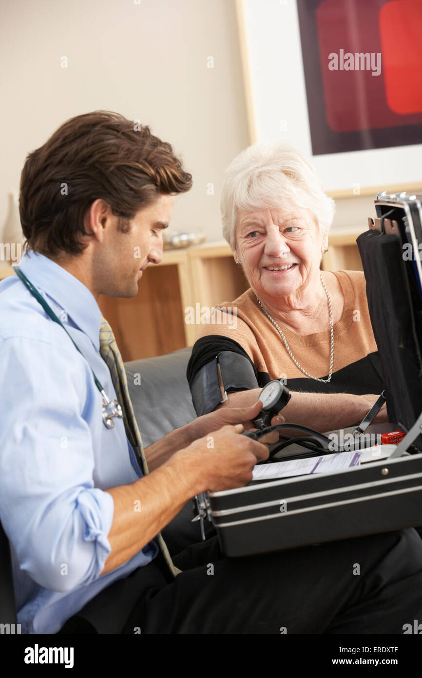 Doctor taking senior woman's blood pressure at home Stock Photo