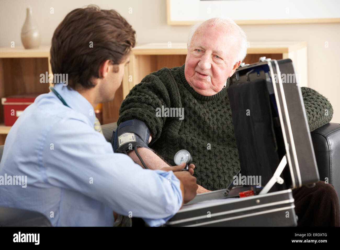 Doctor taking senior man's blood pressure at home Stock Photo
