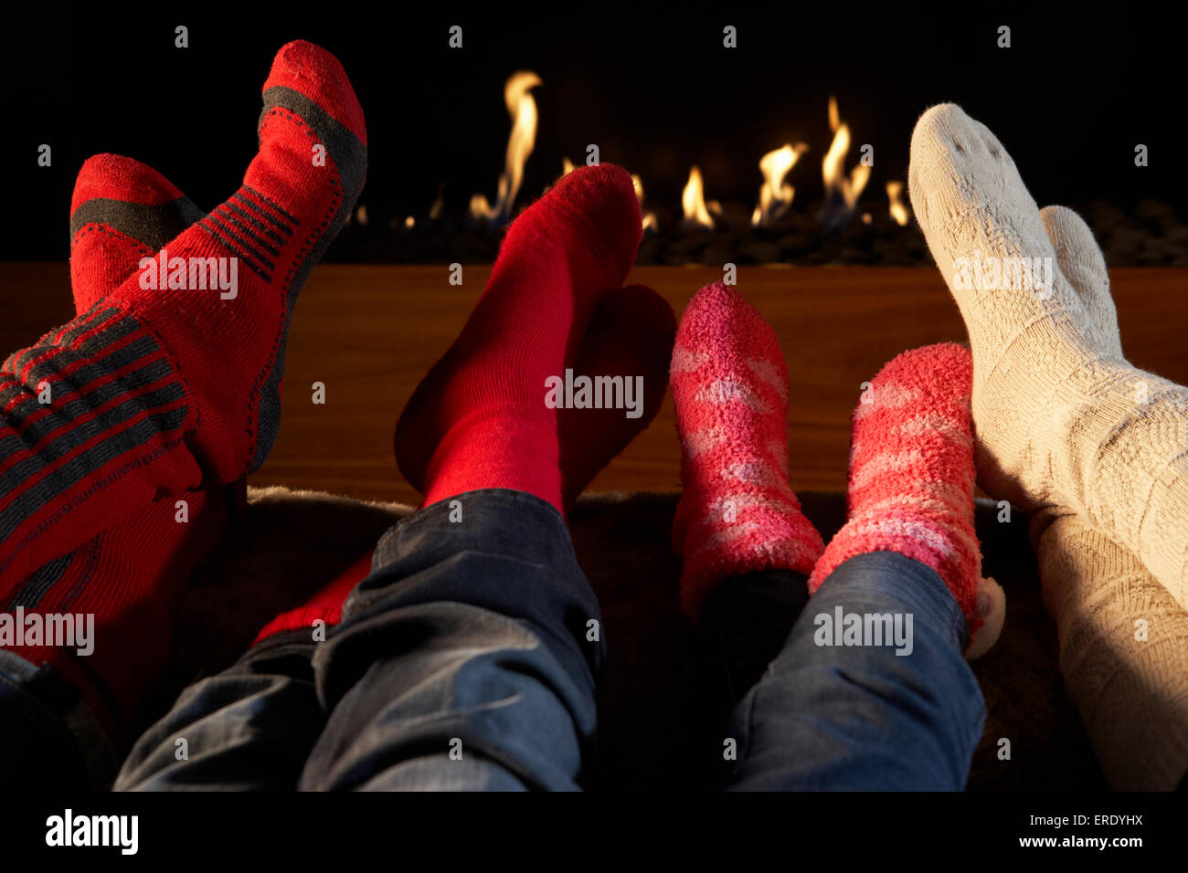 Four pairs feet in socks warming by fire Stock Photo