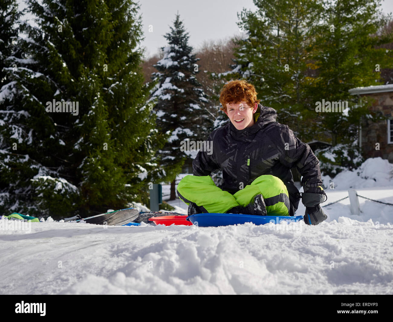 Caucasian teenage boy sledding on snowy hill Stock Photo