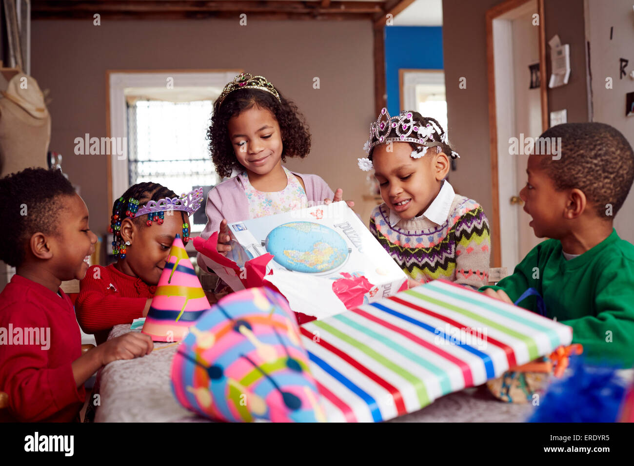 Children wearing tiaras and opening gifts Stock Photo