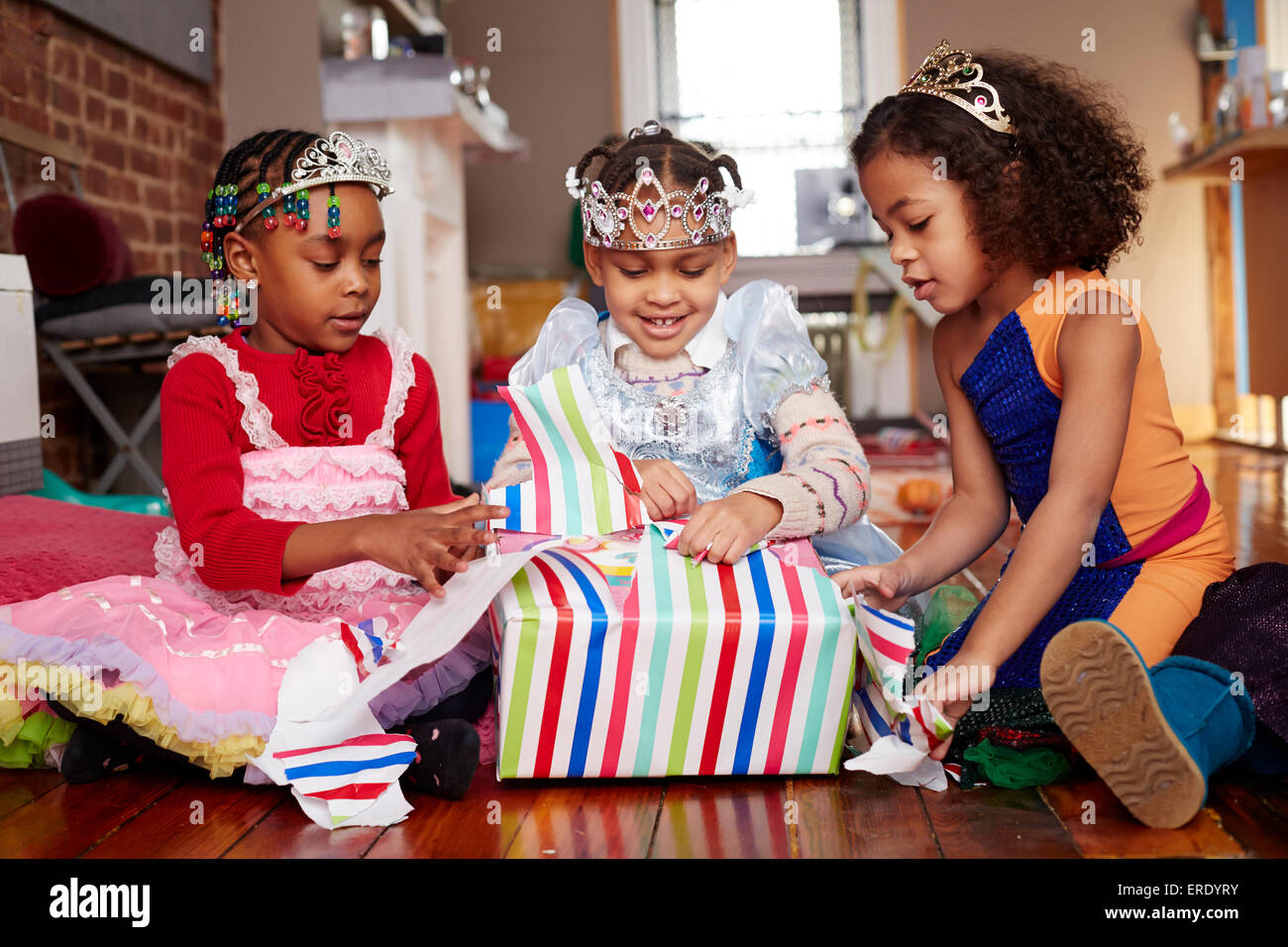 Girls with tiaras opening gifts at party Stock Photo