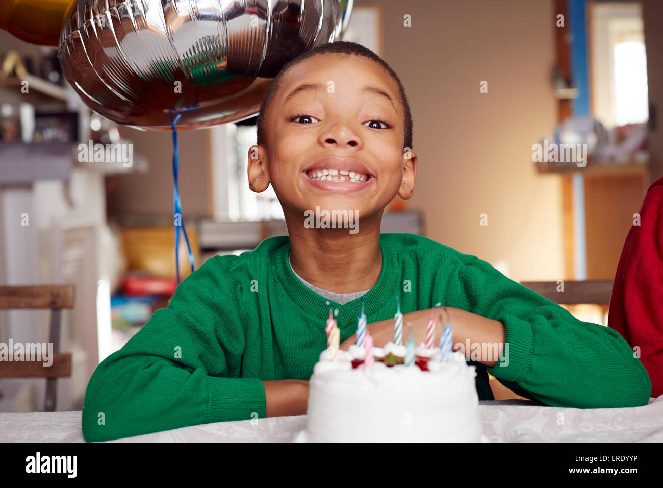 Black boy smiling with balloon and cake at party Stock Photo