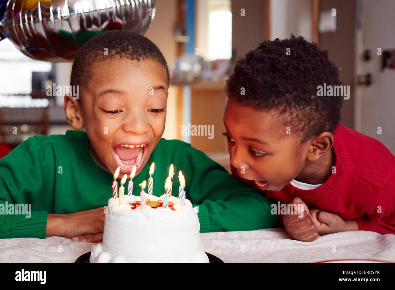 Black boys blowing out cake candles at party Stock Photo