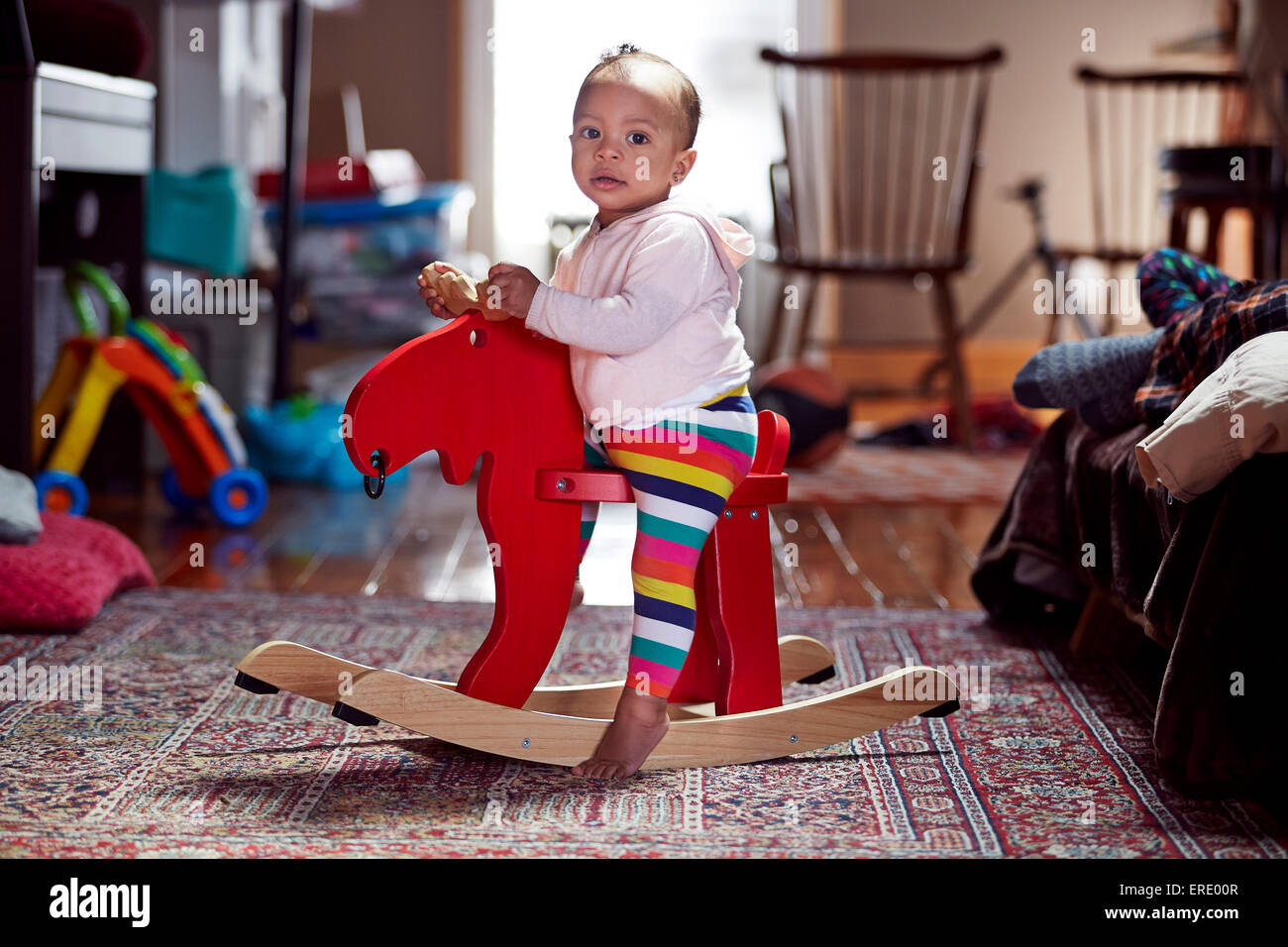 Mixed race baby girl playing on rocking horse Stock Photo