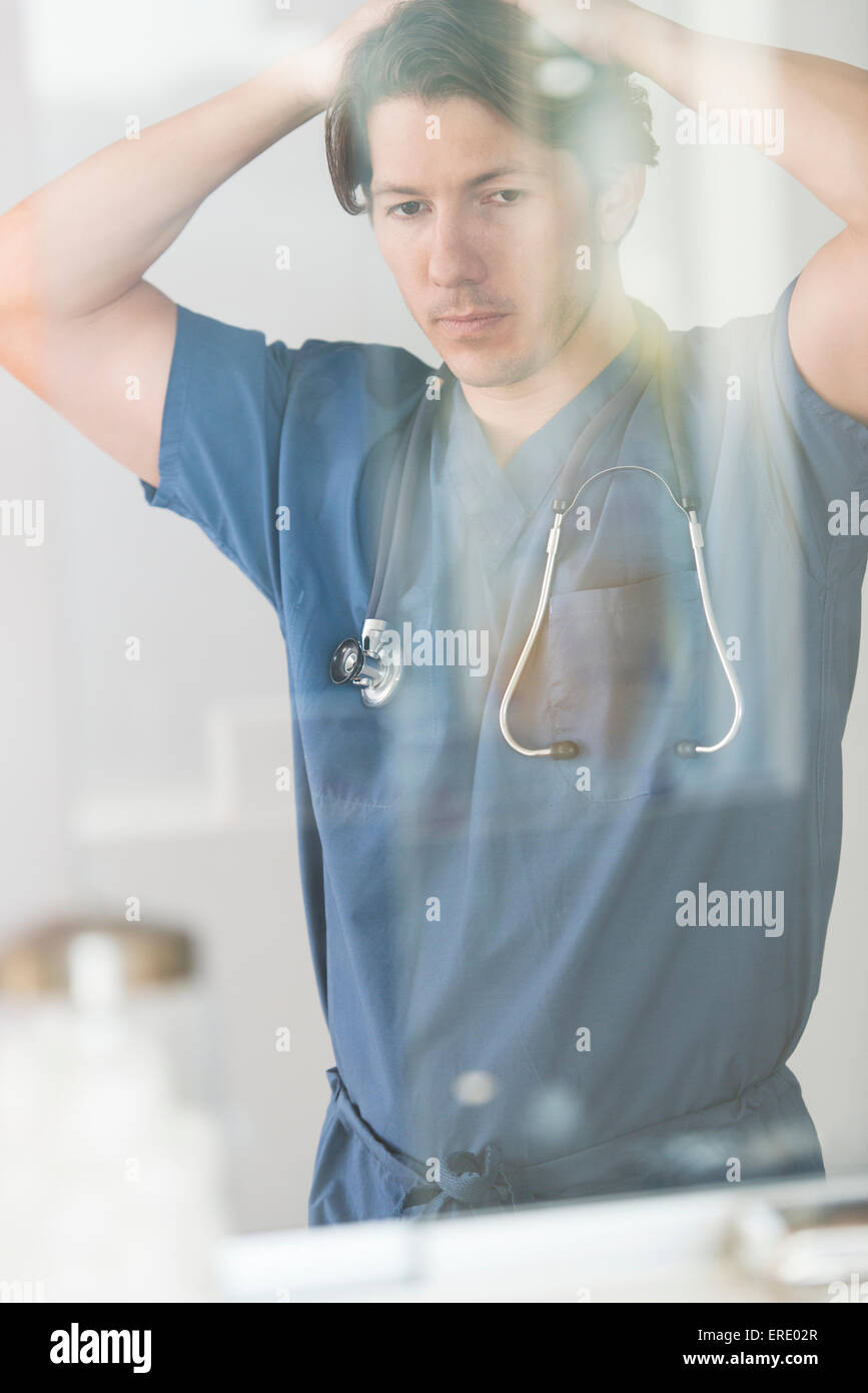 Hispanic doctor with hands on head thinking in hospital Stock Photo