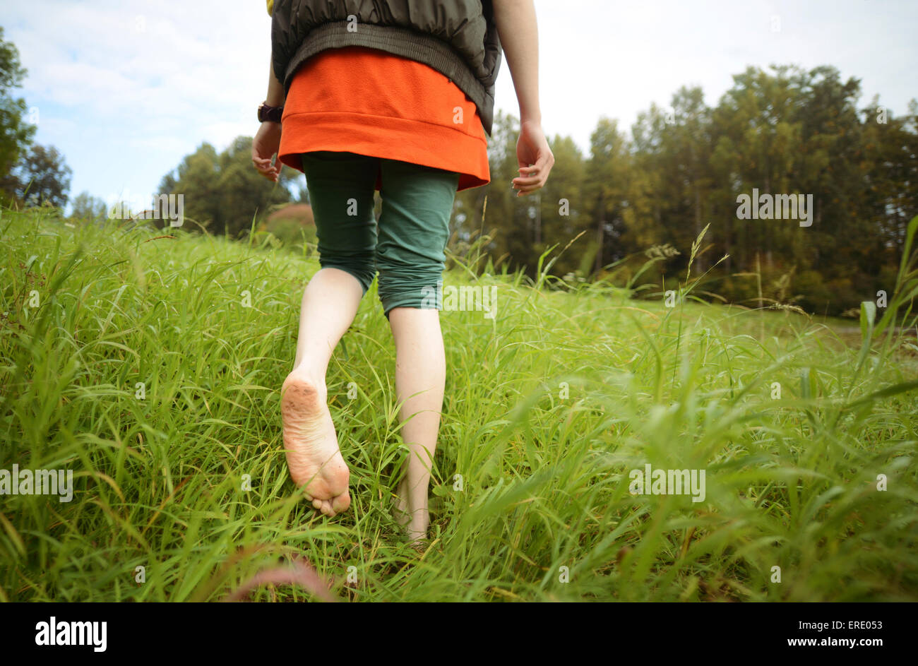 Close up of barefoot Caucasian woman walking in park Stock Photo