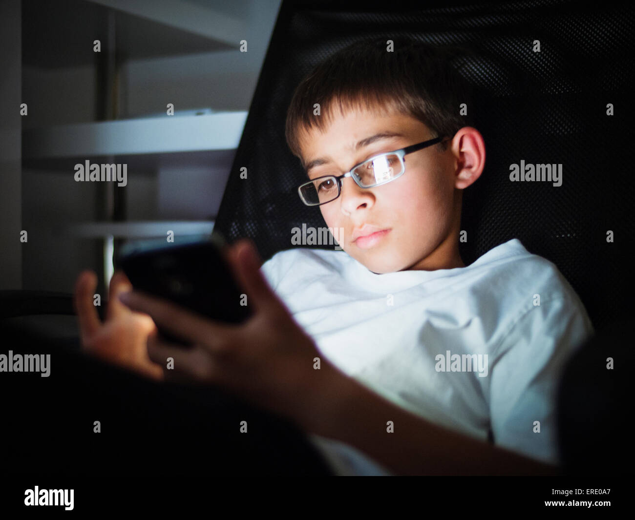 Mixed race boy texting on cell phone at night Stock Photo