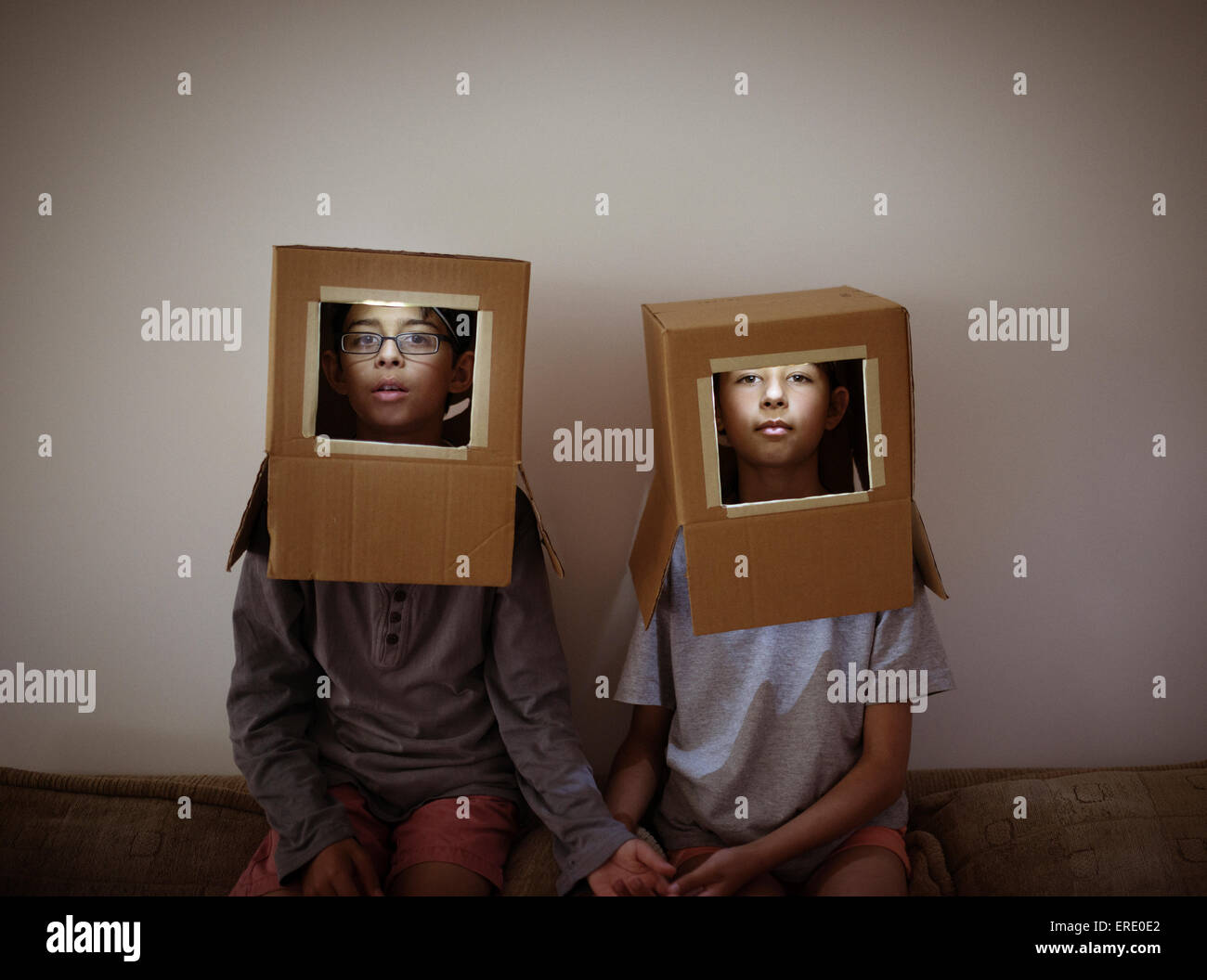 Mixed race brother and sister wearing cardboard box astronaut helmets Stock Photo