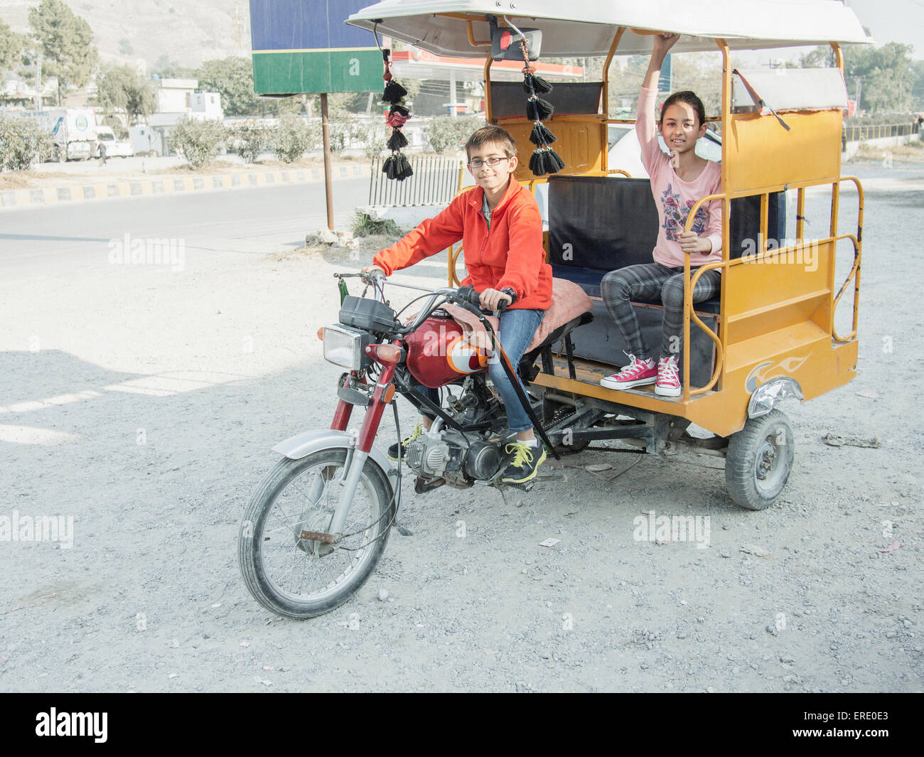 Mixed race boy driving girl in rickshaw Stock Photo