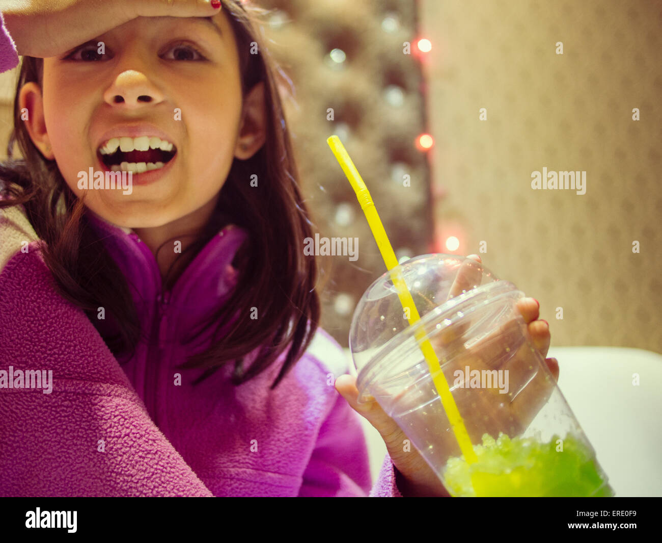Mixed race girl with brain freeze drinking frozen drink Stock Photo